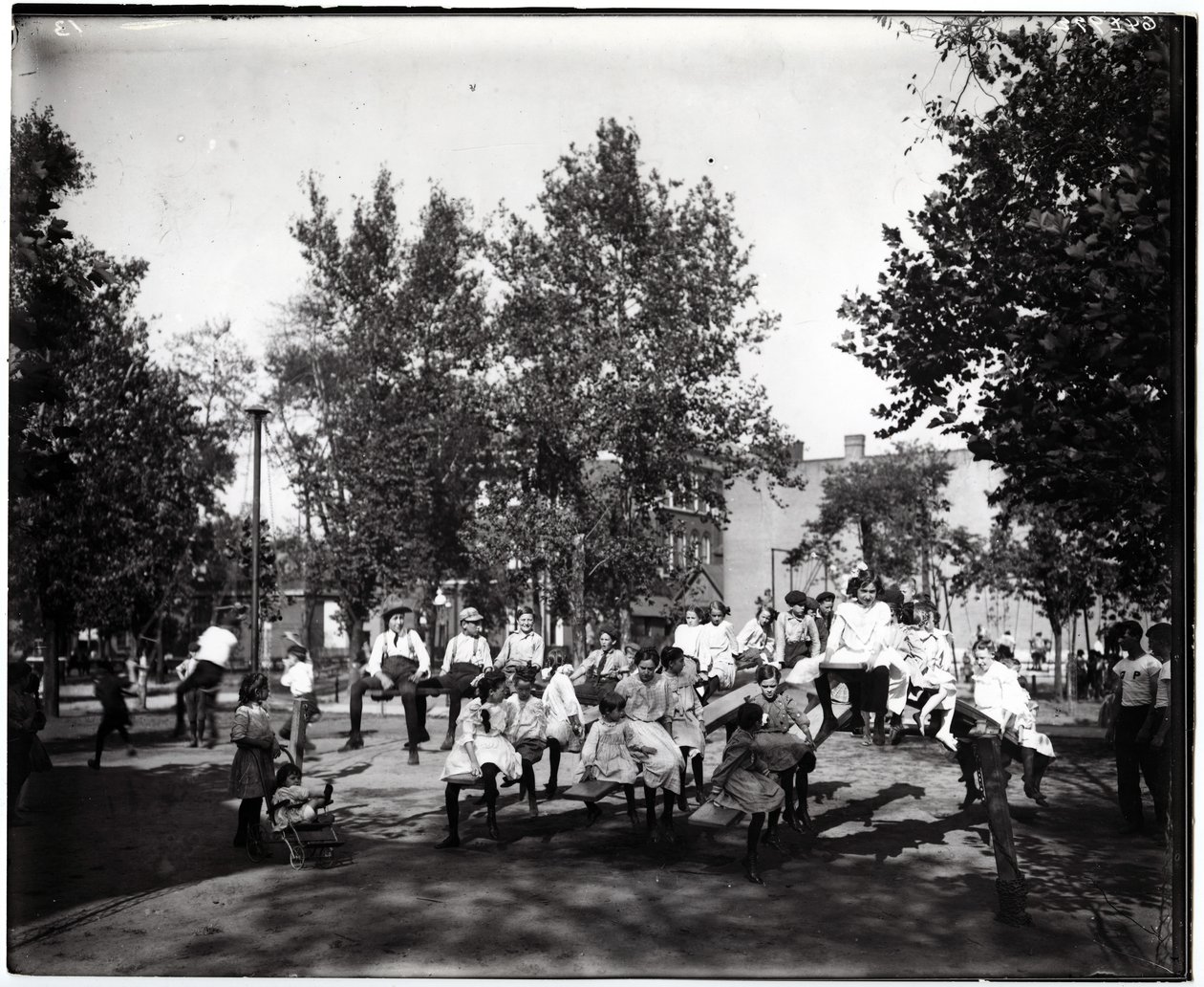 Horizontal, black and white photograph showing children playing on seesaws in an unidentified park av Unknown