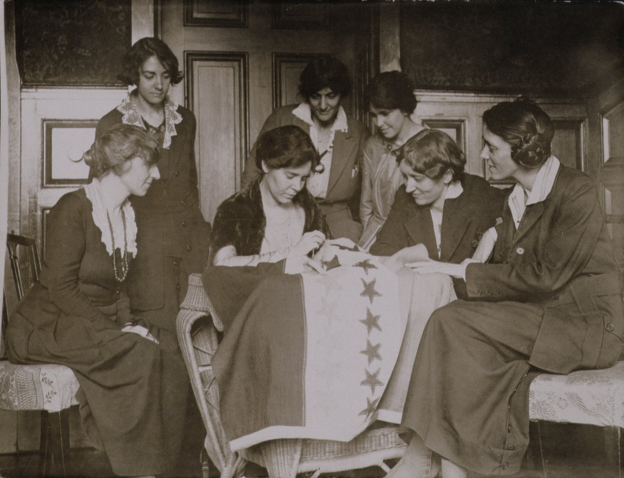 Alice Paul sewing stars on the suffrage flag as other women look on, c.1920  av American Photographer