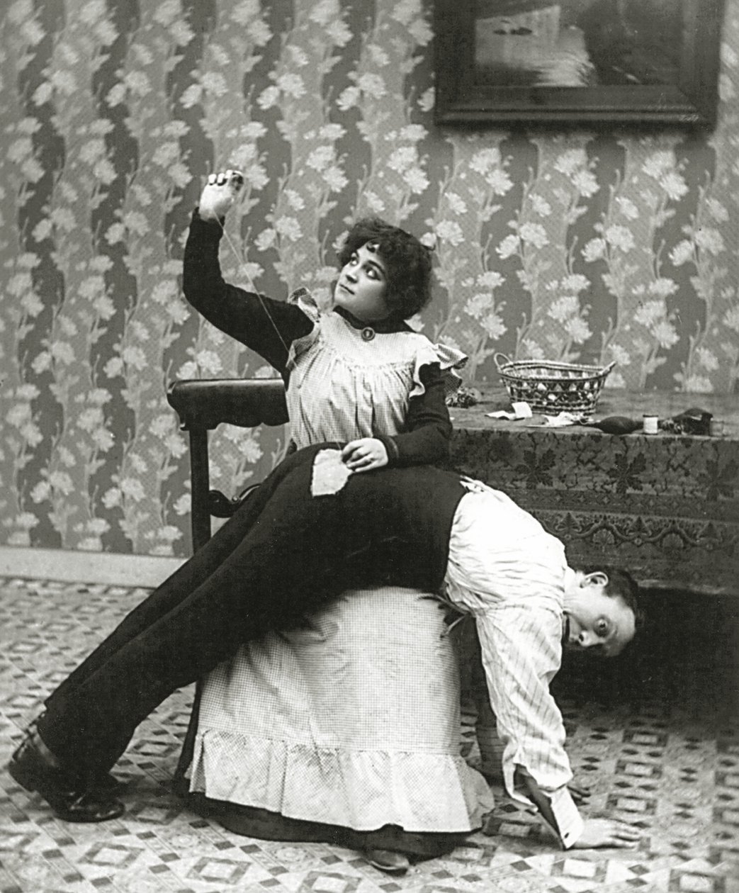 Kvinna som syr en reva på en mans byxor, c.1895 av American Photographer