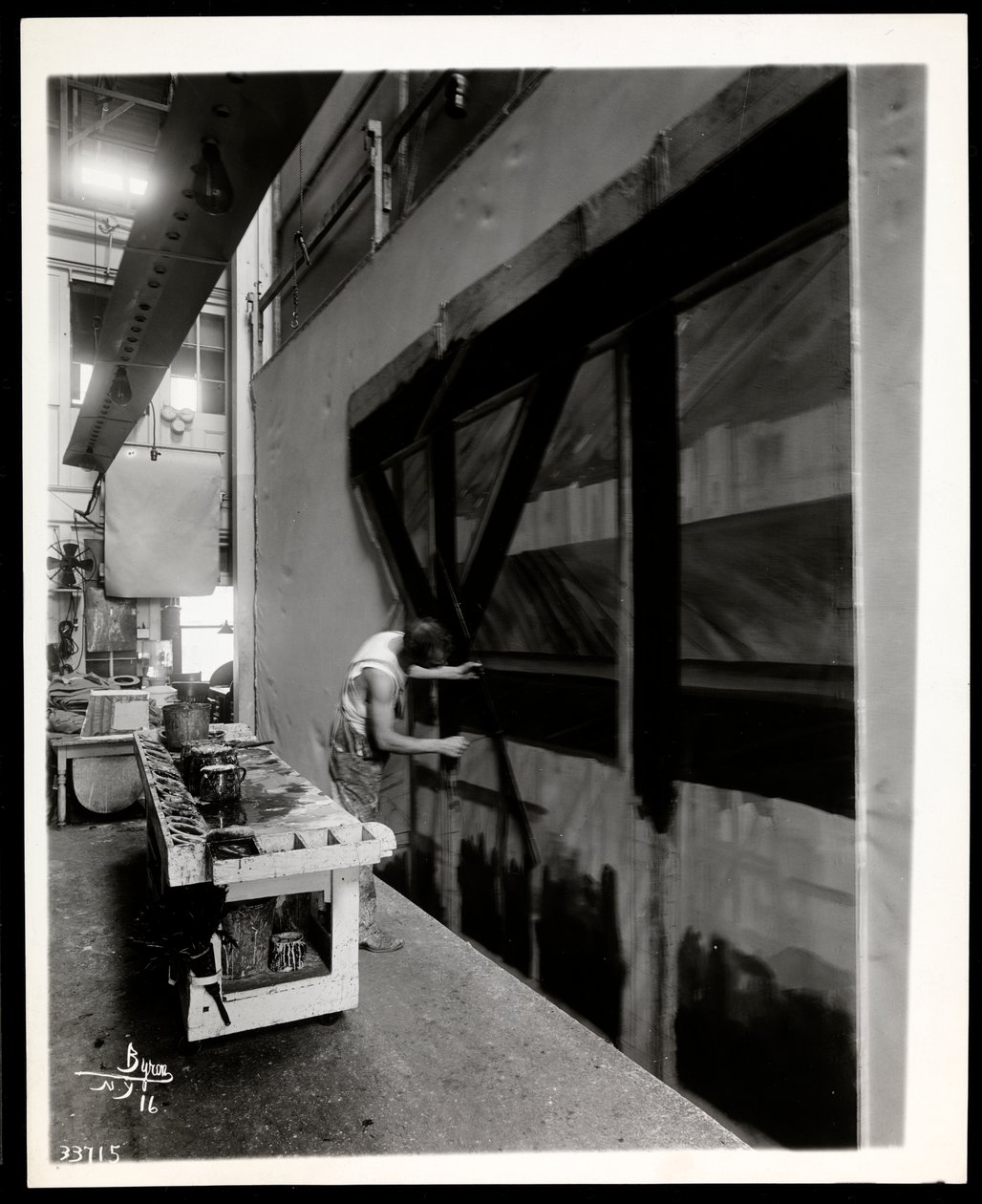 En scenisk konstnär som målar en lägenhet i en scenbutik, New York, 1915-196 (silvergelatintryck) av Byron Company