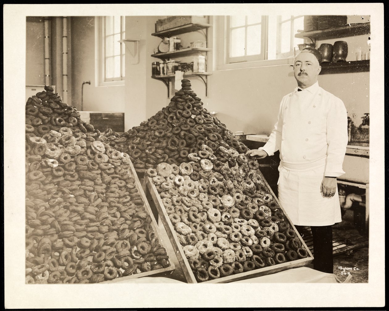 Porträtt av kocken Leoni med containrar med munkar för Frälsningsarmén på Hotel Commodore, 1919 (silvergelatintryck) av Byron Company