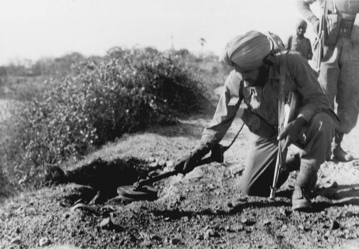En indisk soldat söker efter minor med en metalldetektor av English Photographer