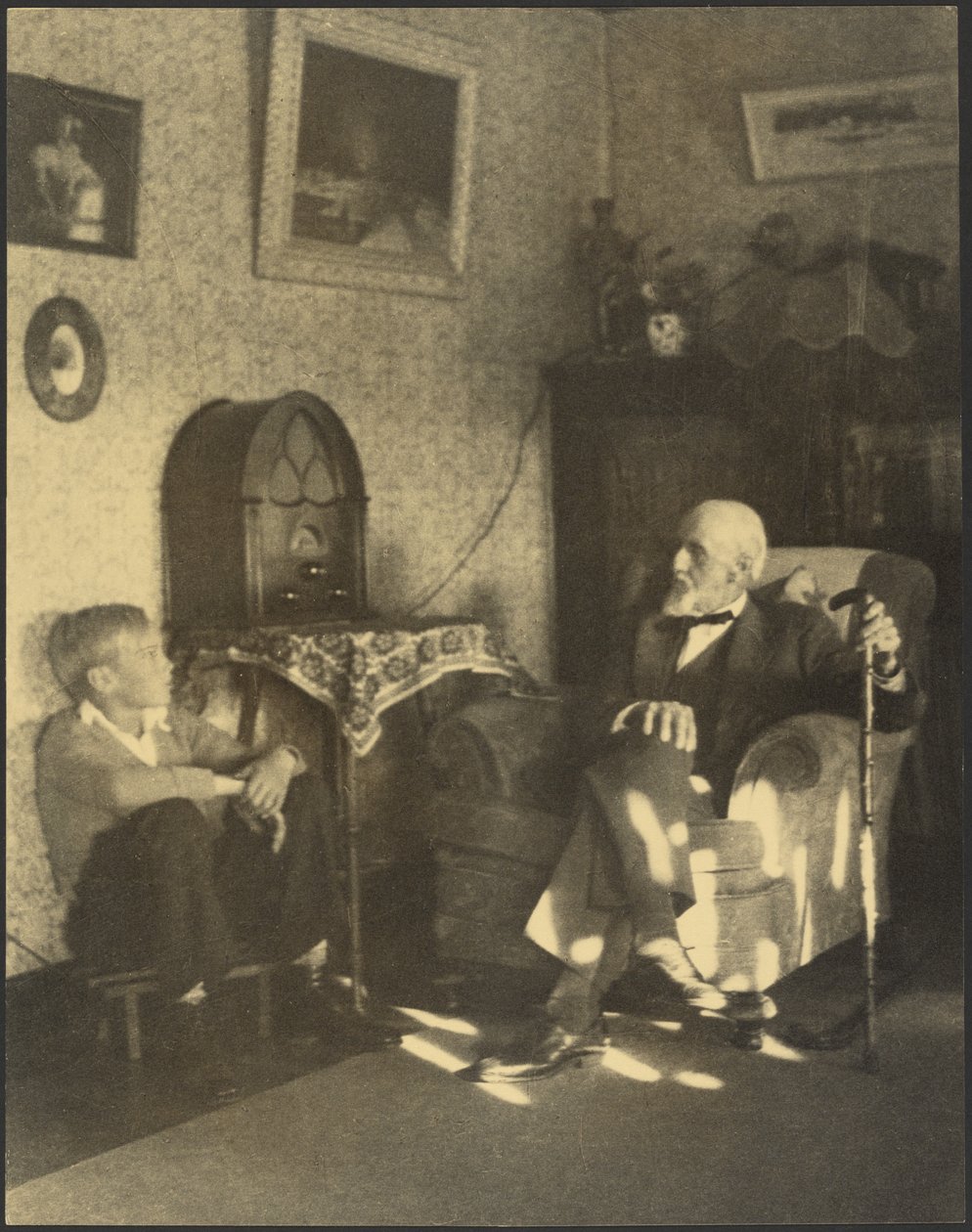 [Man och pojke sitter i ett arbetsrum] av Louis Fleckenstein