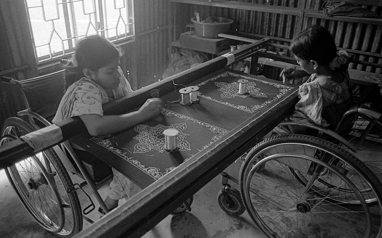 Två fysiskt handikappade tjejer sysslar med broderi på kläderna på The Center for the Rehabilitation of the Paralysed, CRP i Savar, Dhaka, Bangladesh. 2005. av Unbekannt Unbekannt