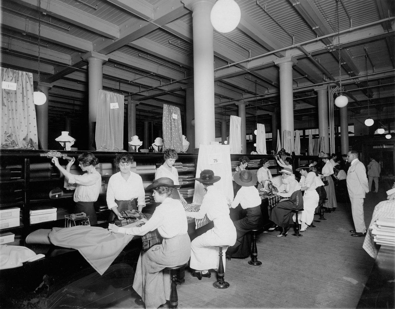 Interior of fabric store. Measuring and cutting fabric for customers av W.C. Persons